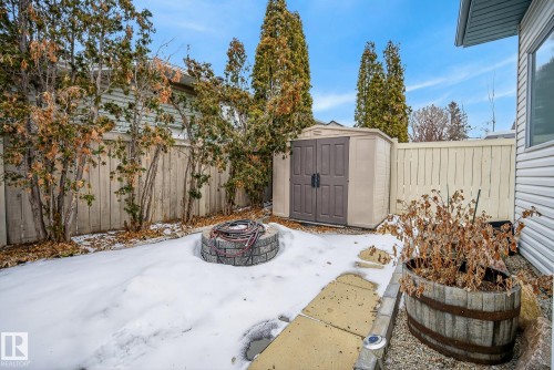 The property features a fenced yard with a storage shed, a stone fire pit, and a planted barrel - 17204 113 Street, Edmonton, AB - Outdoor