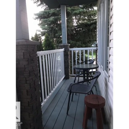 The property features an outdoor deck with white railings and stone-clad pillars, providing space for outdoor seating - 17204 113 Street, Edmonton, AB - Outdoor With Deck Patio Veranda With Exterior