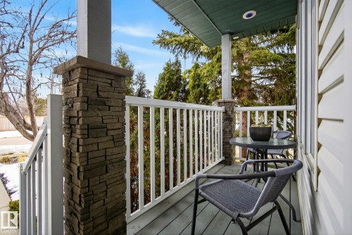 Inviting outdoor porch with durable siding and stone-clad pillars, featuring a wooden floor and white railings - 17204 113 Street, Edmonton, AB - Outdoor With Deck Patio Veranda With Exterior