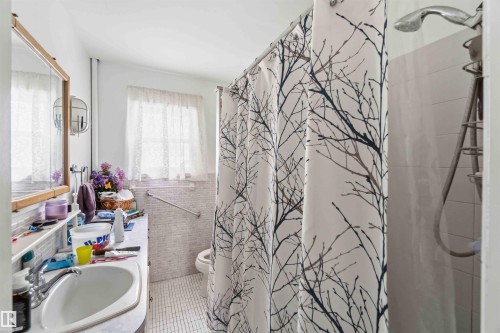Bathroom featuring a vanity with a sink, a window with curtains, and a shower with a showerhead - 10186 143 Street, Edmonton, AB - Indoor Photo Showing Bathroom