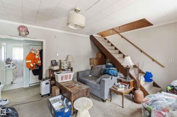 This room features a staircase with a wooden handrail, a ceiling light fixture, and a doorway leading to an additional space - 