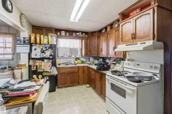 The kitchen features wood cabinetry, a white range with an overhead vent, and a black refrigerator - 