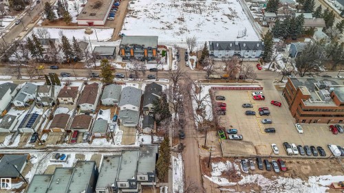 Aerial view showcasing the neighborhood, featuring residential properties, roads, and a commercial building with a surface parking lot - 10186 143 Street, Edmonton, AB - Outdoor With View