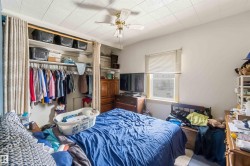 Bedroom with a window featuring blinds, a ceiling fan, and a built-in closet with a curtain - 