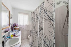 Bathroom featuring a vanity with a sink, a window with curtains, and a shower with a showerhead - 