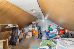 The property features an attic with sloped wood paneling on the ceiling and a visible brick chimney structure - 