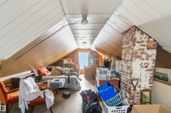 This room features sloped white paneled ceilings and wood paneled walls, with a visible brick chimney structure - 