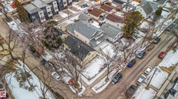 Aerial view of the property and its surrounding streets, featuring residential buildings and tree-lined sidewalks - 