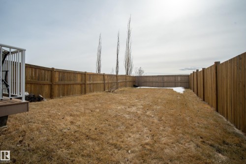 The property features a spacious yard with a wooden fence and a deck with white railings - 9051 Scott Crescent, Edmonton, AB - Outdoor