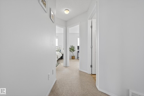 Well-lit hallway featuring light-colored carpet flooring and white walls, with recessed lighting providing ambient illumination - 9051 Scott Crescent, Edmonton, AB - Indoor Photo Showing Other Room