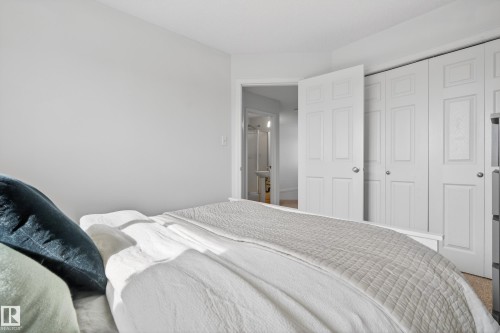 This room features light-colored walls, white bi-fold closet doors, and light-colored carpeting - 9051 Scott Crescent, Edmonton, AB - Indoor Photo Showing Bedroom