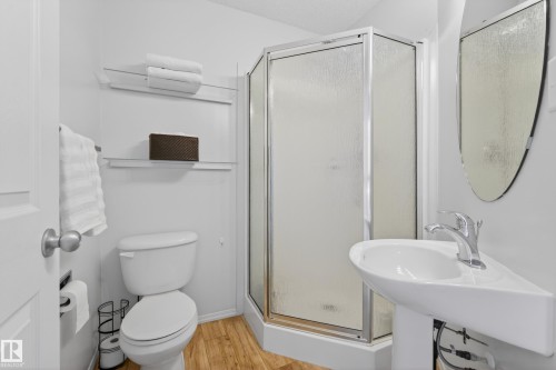 Bathroom featuring a corner shower, a toilet, and a pedestal sink with a faucet - 9051 Scott Crescent, Edmonton, AB - Indoor Photo Showing Bathroom