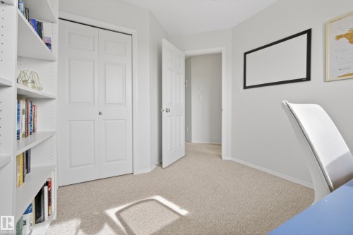 Bright room featuring neutral carpeting and light-colored walls, with a white bookshelf and closet doors - 9051 Scott Crescent, Edmonton, AB - Indoor Photo Showing Other Room