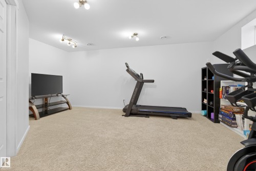 This versatile room offers an expansive carpeted area, light-colored walls, and recessed lighting, providing an adaptable space for various uses - 9051 Scott Crescent, Edmonton, AB - Indoor Photo Showing Gym Room