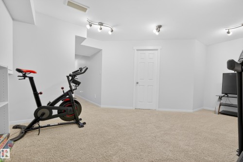 This versatile room features neutral carpeting, recessed lighting, and a white paneled door - 9051 Scott Crescent, Edmonton, AB - Indoor Photo Showing Gym Room