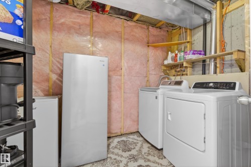 Dedicated laundry area featuring a washer and dryer, complemented by additional refrigeration units and shelving for storage - 9051 Scott Crescent, Edmonton, AB - Indoor Photo Showing Laundry Room