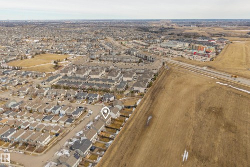 Aerial view showcasing the residential neighbourhood, a commercial area with buildings and parking, and a roadway - 9051 Scott Crescent, Edmonton, AB - Outdoor With View