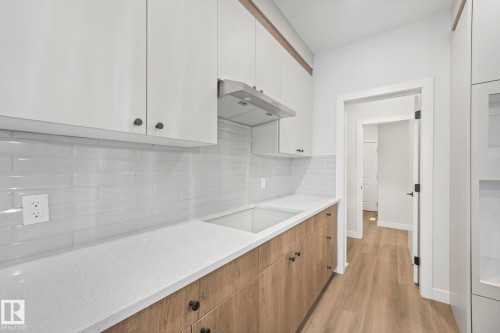 The kitchen features white upper cabinetry, light wood lower cabinetry, and a white subway tile backsplash - 14 Dalquist Bay, Leduc, AB - Indoor Photo Showing Kitchen