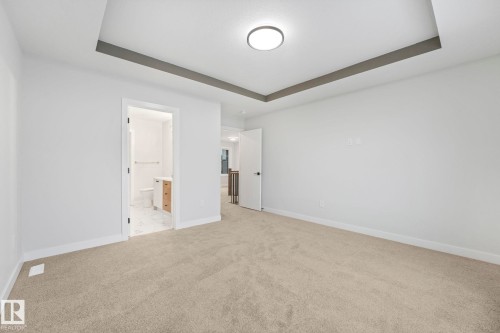 This room features a recessed ceiling with a contemporary light fixture, neutral carpet flooring, and white walls - 14 Dalquist Bay, Leduc, AB - Indoor Photo Showing Other Room