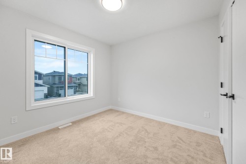 This room features neutral-toned carpeting, light-colored walls, and a window with white trim providing views of the surrounding neighborhood - 14 Dalquist Bay, Leduc, AB - Indoor Photo Showing Other Room