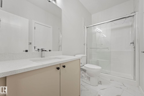Bathroom featuring a vanity with a light-colored countertop and integrated sink, a large mirror, a toilet, and a shower with a clear glass enclosure - 14 Dalquist Bay, Leduc, AB - Indoor Photo Showing Bathroom