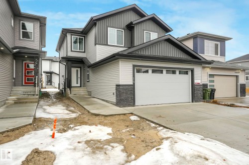 The property features a two-story design with a light gray and dark gray exterior, complemented by stone accents - 14 Dalquist Bay, Leduc, AB - Outdoor With Facade