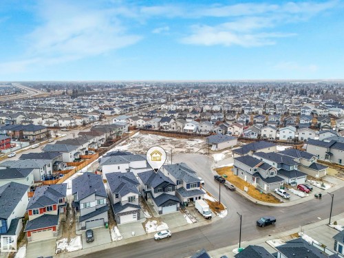 Aerial view of the property and its surrounding neighborhood, showcasing a residential street and a large undeveloped lot nearby - 14 Dalquist Bay, Leduc, AB - Outdoor With View