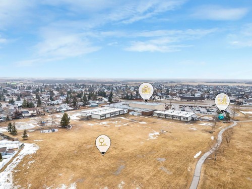 Aerial view of the surrounding landscape, featuring a paved path, open fields, and buildings with parking facilities - 14 Dalquist Bay, Leduc, AB - Outdoor With View