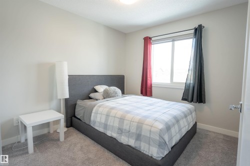 This room features light grey wall paint, a window providing natural light, and grey carpeting - 656 Black Stone, Leduc, AB - Indoor Photo Showing Bedroom