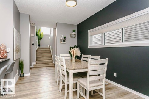 This dining area features light-colored flooring, a contrasting dark accent wall, and windows with blinds - 320 Balsam Link, Leduc, AB - Indoor Photo Showing Dining Room