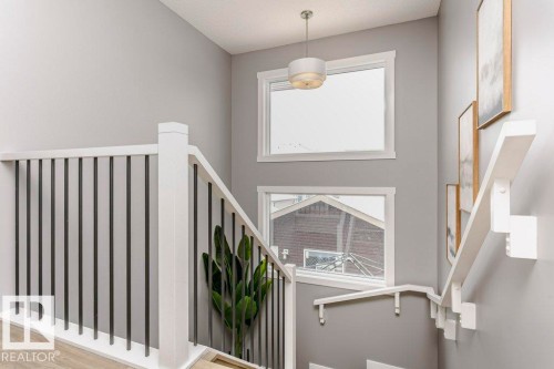 Staircase featuring white railings with black spindles, light grey walls, and windows providing natural light - 320 Balsam Link, Leduc, AB - Indoor Photo Showing Other Room