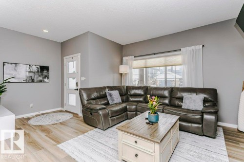 Living area featuring light wood flooring, light grey walls, and a large window with white curtains - 320 Balsam Link, Leduc, AB - Indoor Photo Showing Living Room