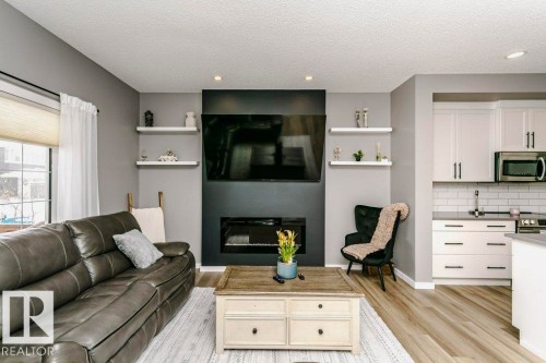 Living area featuring a modern black fireplace, recessed lighting, and light-colored flooring - 320 Balsam Link, Leduc, AB - Indoor Photo Showing Living Room With Fireplace