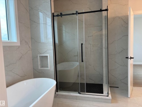 Modern bathroom featuring a freestanding tub and a glass-enclosed shower with black hardware - 1039 151 Ave, Edmonton, AB 