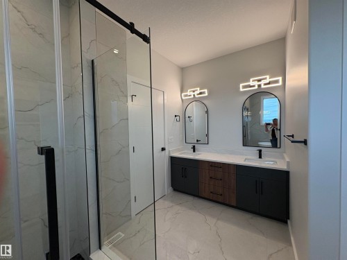 Modern bathroom featuring a double vanity with quartz countertops, undermount sinks, and matte black fixtures - 1039 151 Ave, Edmonton, AB 