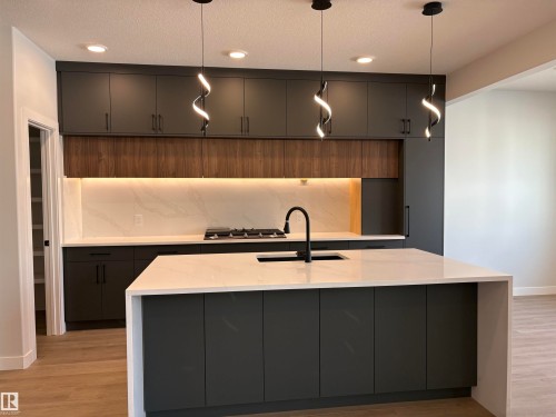 Modern kitchen featuring an expansive island with a waterfall countertop - 1039 151 Ave, Edmonton, AB 