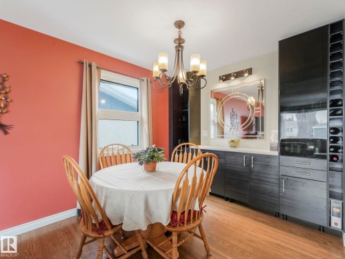 This dining area features laminate darker floors and a modern chandelier - 16106 79A Avenue Nw, Edmonton, AB - Indoor Photo Showing Dining Room