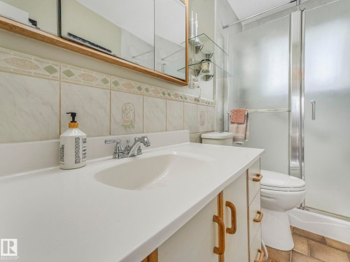 The bathroom features a vanity with an integrated sink, a chrome faucet, and a tiled backsplash - 16106 79A Avenue Nw, Edmonton, AB - Indoor Photo Showing Bathroom