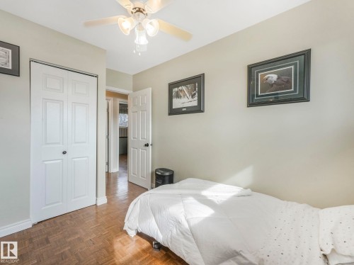 This room features parquet flooring, a ceiling fan with integrated lighting, and white bi-fold closet doors - 16106 79A Avenue Nw, Edmonton, AB - Indoor Photo Showing Bedroom