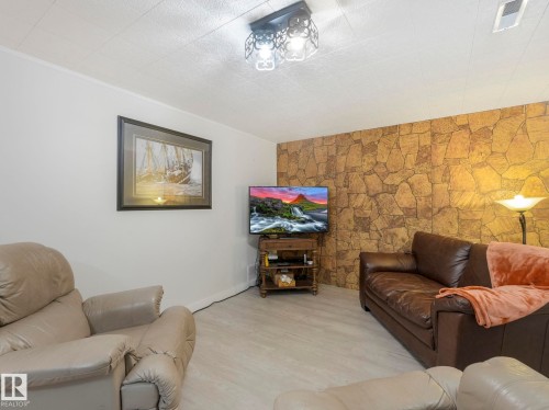 This living area features a textured accent wall and light-colored flooring - 16106 79A Avenue Nw, Edmonton, AB - Indoor Photo Showing Living Room