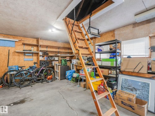 This property features a spacious utility area with a concrete floor, built-in shelving, and a window with blinds - 16106 79A Avenue Nw, Edmonton, AB - Indoor Photo Showing Garage