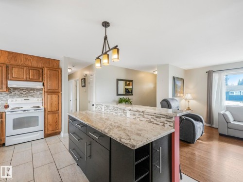 The kitchen features light-toned wooden cabinetry, a white range, and a tiled backsplash - 16106 79A Avenue Nw, Edmonton, AB - Indoor Photo Showing Kitchen