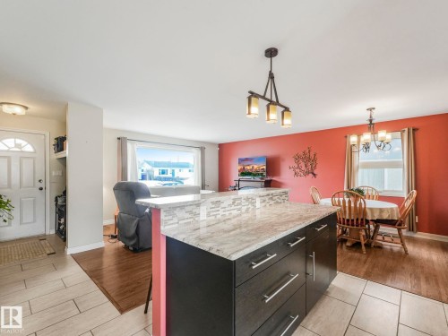 The property features a kitchen island with a granite countertop and a tiled backsplash - 16106 79A Avenue Nw, Edmonton, AB - Indoor