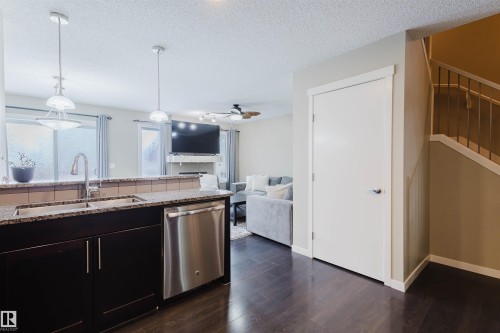 The kitchen features granite countertops, dark cabinetry, a stainless steel dishwasher, and a double basin sink with a gooseneck faucet - 16811 120 Street, Edmonton, AB - Indoor Photo Showing Kitchen With Double Sink