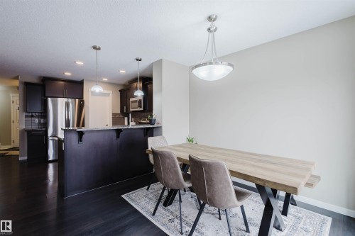 Open concept living space featuring dark wood flooring, a kitchen with dark cabinetry and stainless steel appliances, and a dining area with an overhead light fixture - 16811 120 Street, Edmonton, AB - Indoor Photo Showing Dining Room