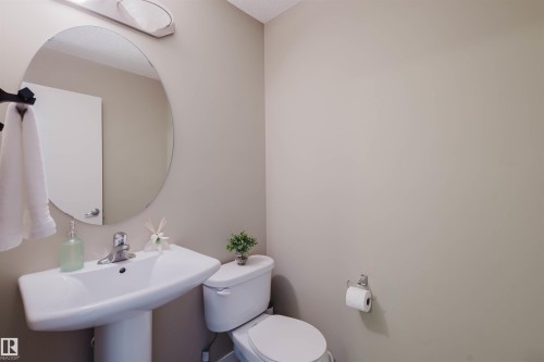 Bathroom featuring a pedestal sink, toilet, and an oval mirror - 16811 120 Street, Edmonton, AB - Indoor Photo Showing Bathroom