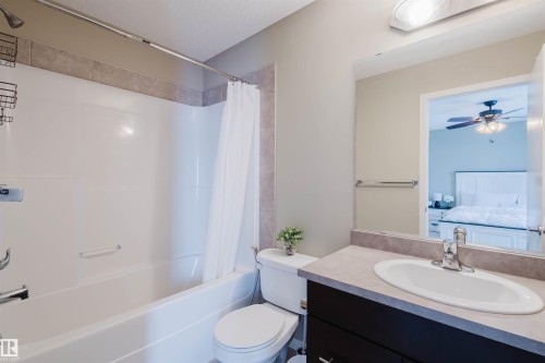 The bathroom features a combination tub and shower with tile surround, a vanity with a white oval sink, and a mirror - 16811 120 Street, Edmonton, AB - Indoor Photo Showing Bathroom