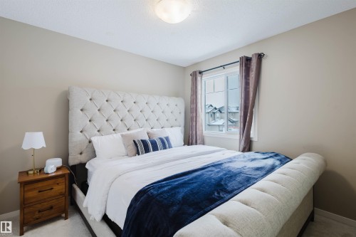 This bedroom features a window with curtains, a ceiling light fixture, and neutral colored walls - 16811 120 Street, Edmonton, AB - Indoor Photo Showing Bedroom