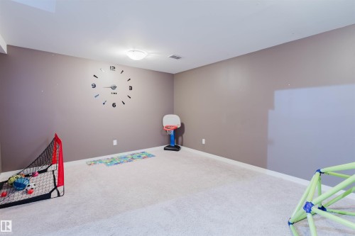 This versatile room features neutral-toned walls, recessed lighting, and light-colored carpeting, providing a bright and adaptable space - 16811 120 Street, Edmonton, AB - Indoor
