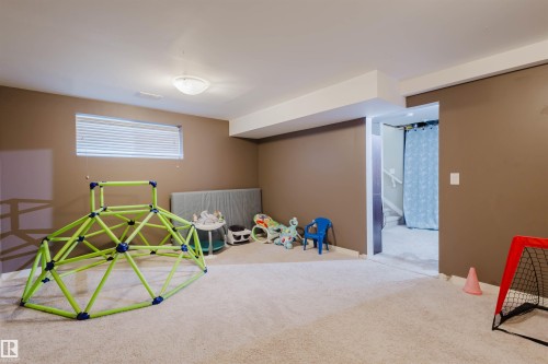 Spacious carpeted room featuring a window with blinds, ceiling lighting, and a doorway leading to another area - 16811 120 Street, Edmonton, AB - Indoor Photo Showing Basement
